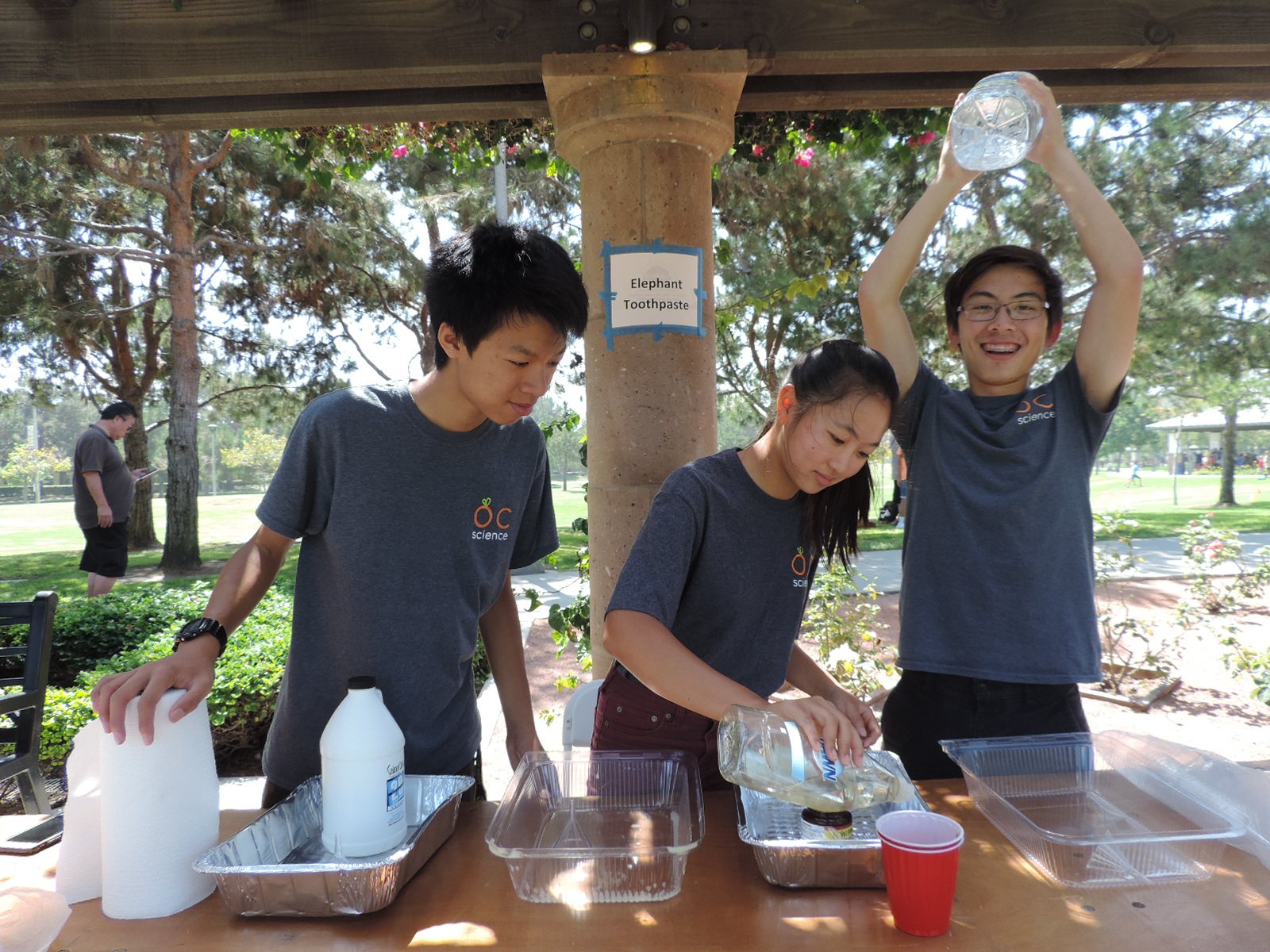 Students pour water between containers during an outdoor science activity.