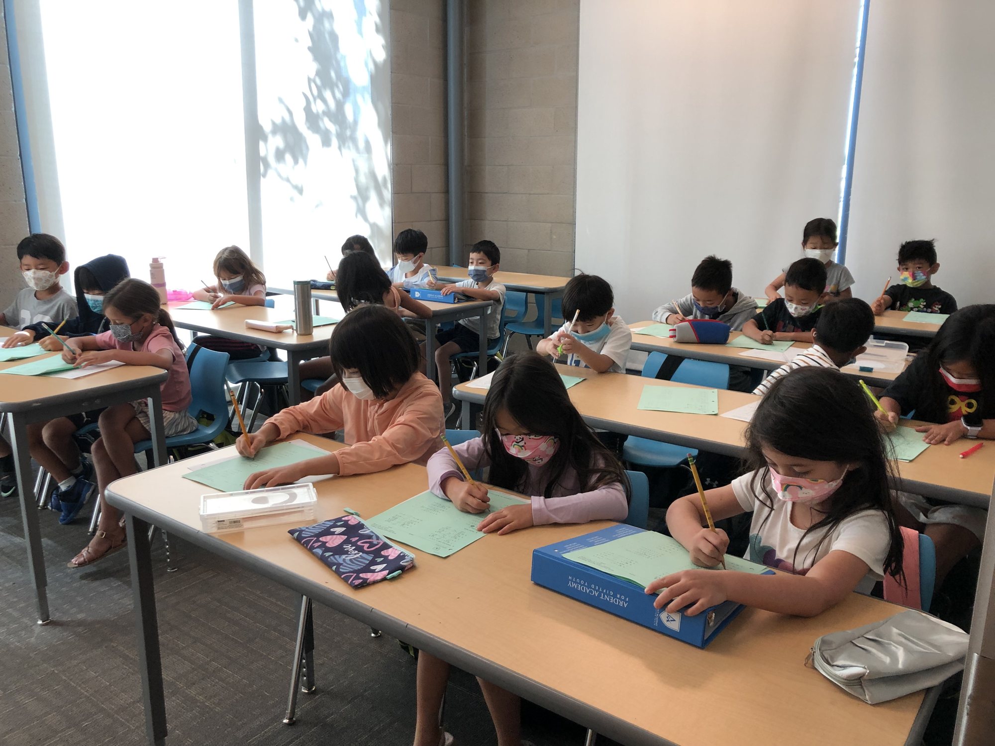 Students in face masks work at their desks in an M202 class.