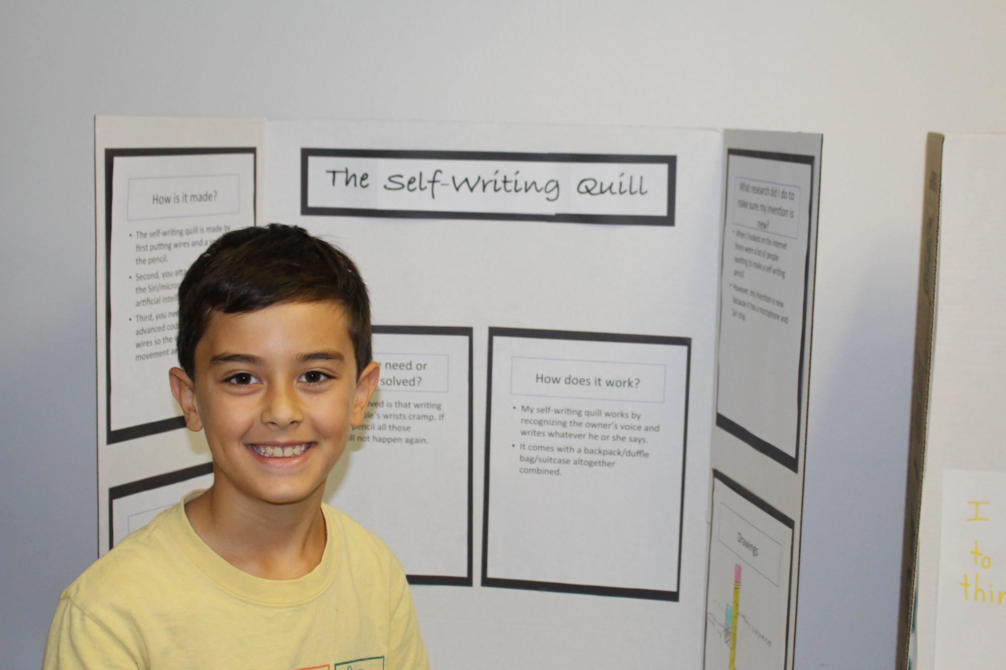 A student smiles in front of his project board, The Self-Writing Quill.