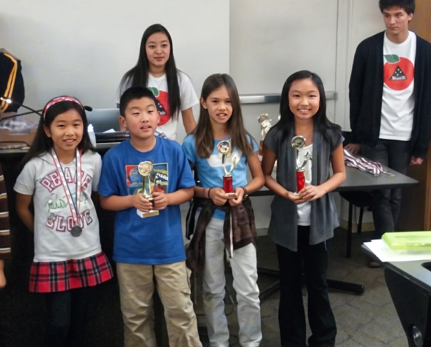 Four young Ardent students standing with contest trophies, two older students behind them.
